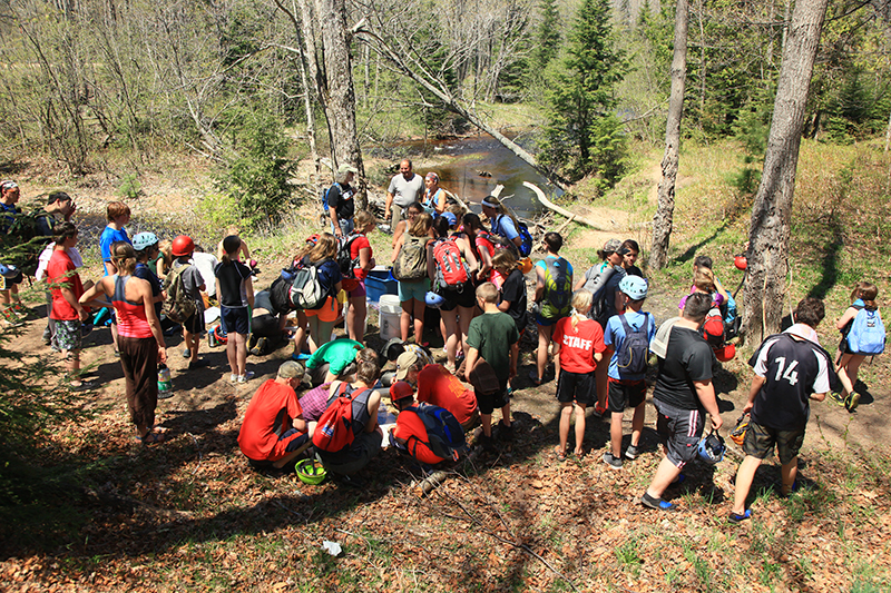 Volunteers and a youth adventure club learning about volunteer stream monitoring with the Yellow Dog.